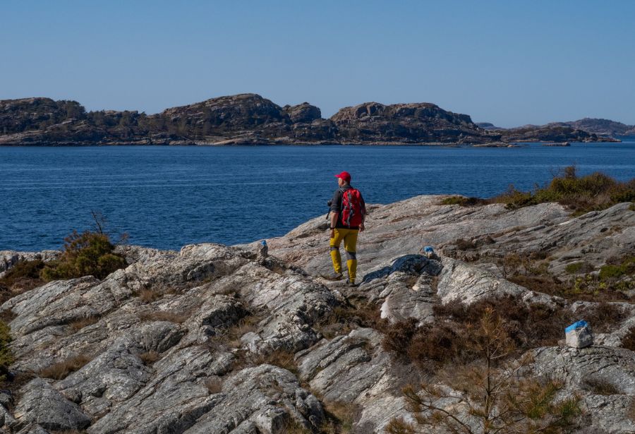 En mann som går på svaberg.