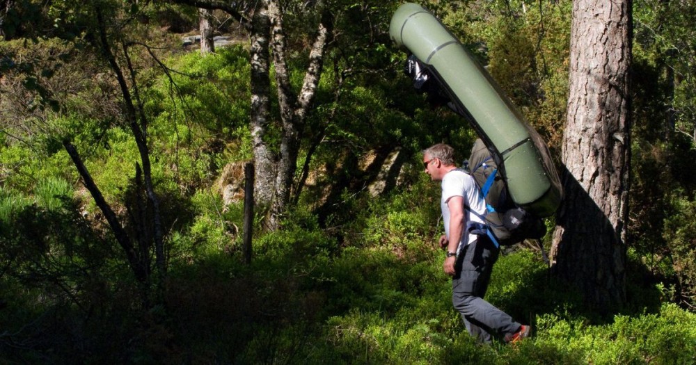 Mann med Packraft på ryggen 