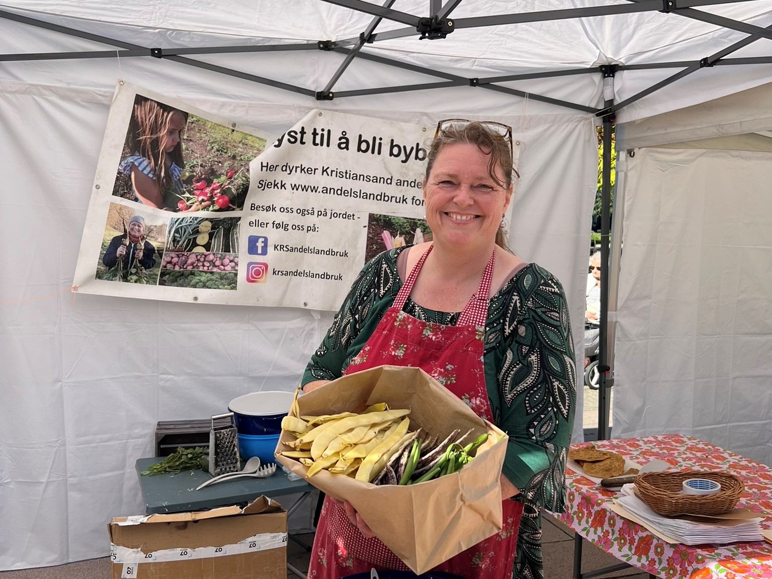 CHeryl holder opp en eske med lokalproduserte grønnsaker. 